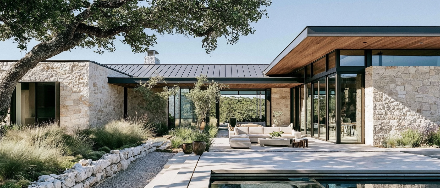 A limestone and glass Hill Country home with wood soffits, oak trees, and a pool